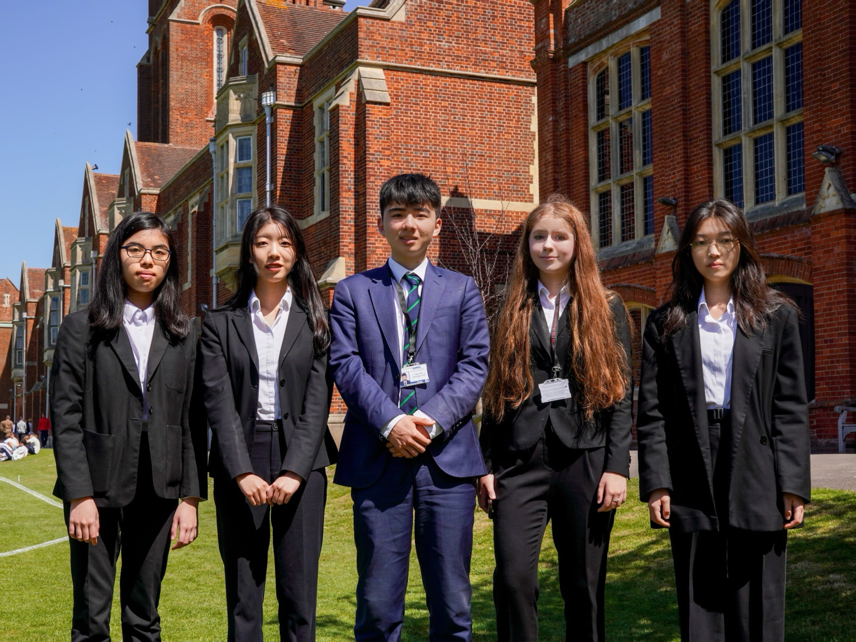 Five year 12 students stand outside Eastbourne College in their school uniforms