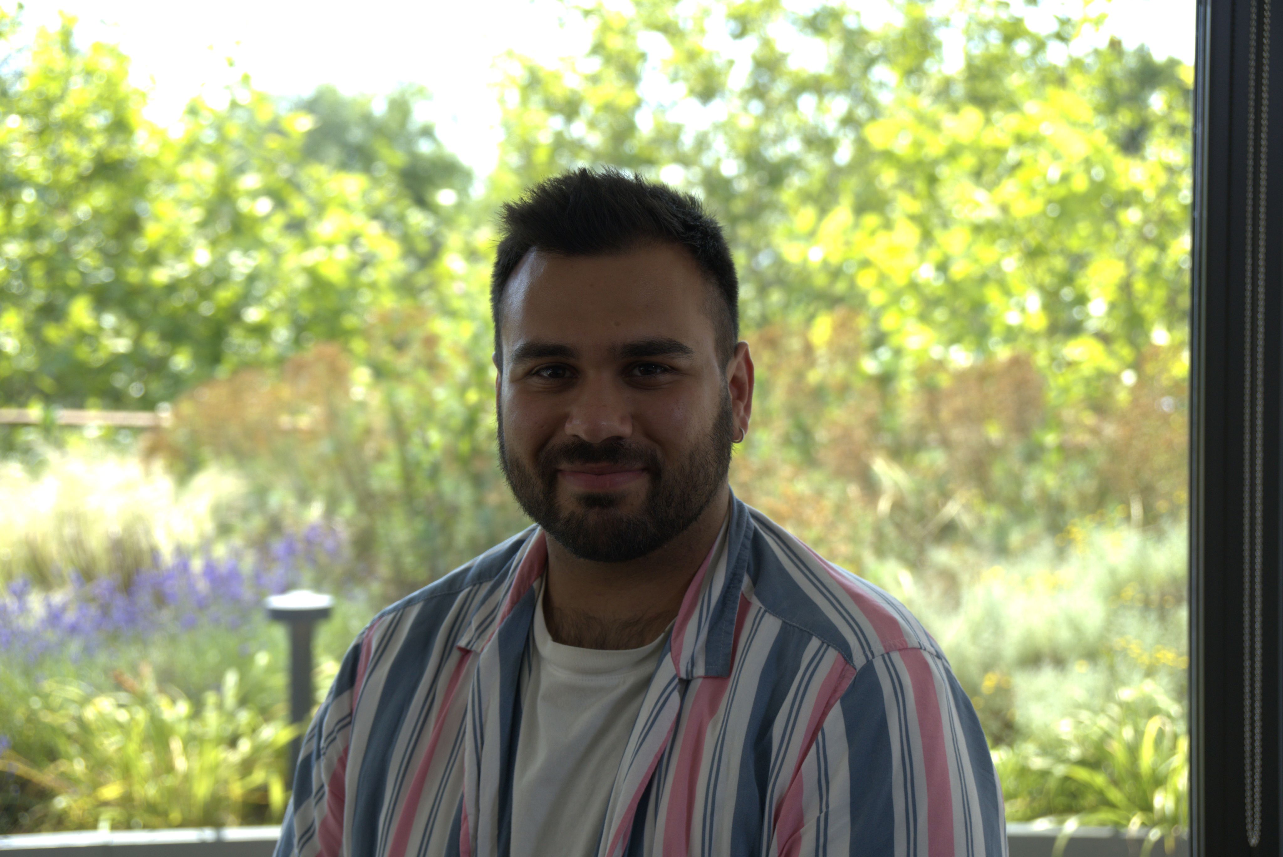 Man in striped pastel coloured shirt smiling at camera