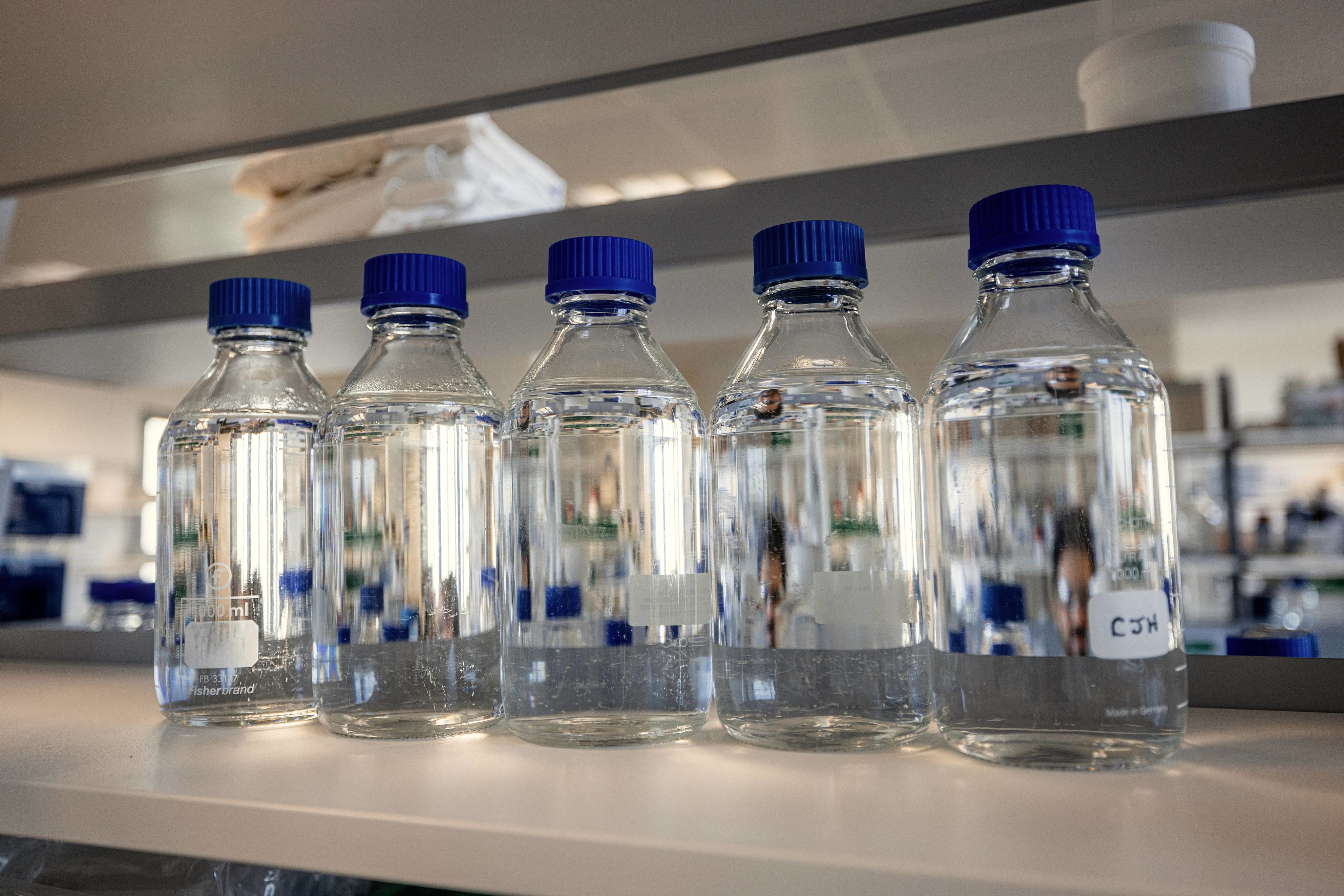 Five glass vials with clear liquid in a lab setting